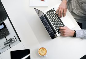 A person is using their laptop on the desk