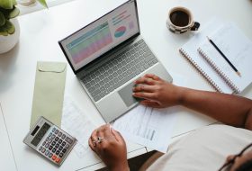 A person using a laptop on top of papers.